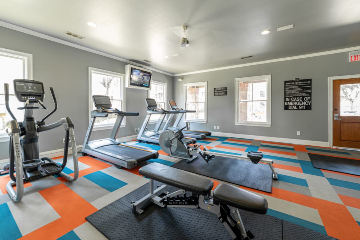 Treadmills, row machine, elliptical, and TV monitor in fitness room at Marquis at Bellaire Ranch in Fort Worth, Texas