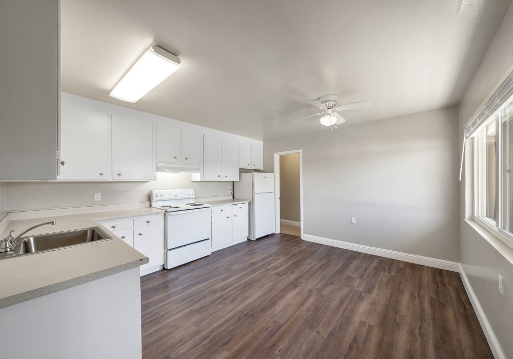 Fully equipped kitchen with wood-style flooring and plenty of counter space at Garden Court Apartments in Alameda, California