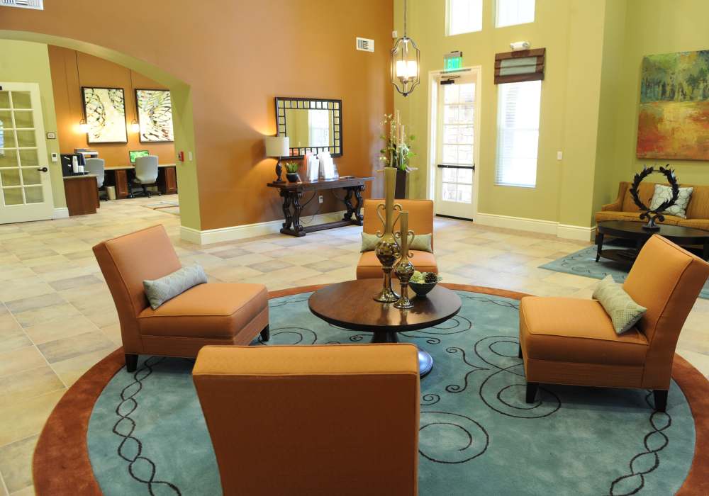 Inviting common area featuring cozy orange armchairs, a stylish round coffee table, and warm, vibrant walls, perfect for relaxation and socialising at Cresta Bella in San Diego, California