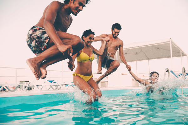 Friends jumping in the pool at Willow Oaks Apartments in Bryan, Texas