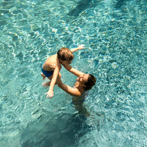 Resident and child playing in the pool at The 603 in Bryan, Texas