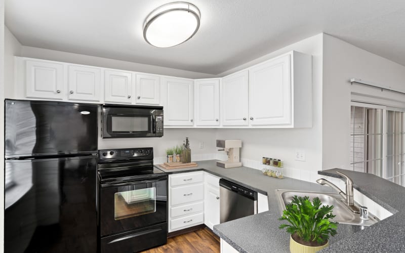 Updated kitchen with white cabinets and black appliances at Autumn Chase Apartments in Vancouver, Washington