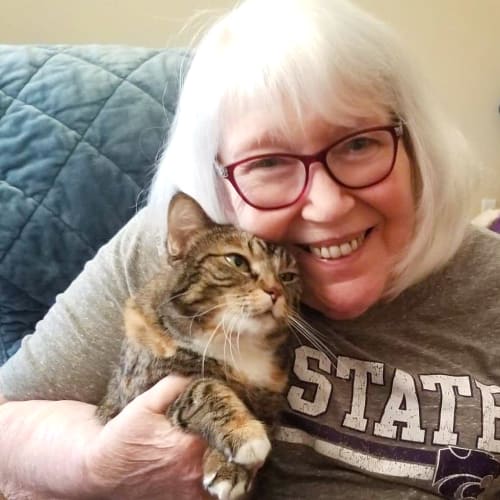 A smiling resident holding her pet cat at The Oxford Grand Assisted Living & Memory Care in Wichita, Kansas