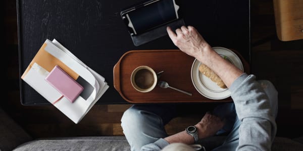 Resident having breakfast and browsing the web on a tablet in their apartment at a WISH community