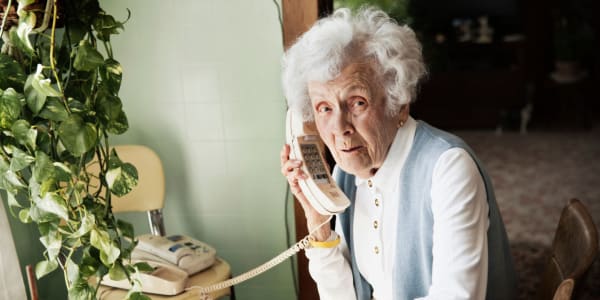 Resident sitting at her dining table talking on home phone at Fair Oaks Health Care Center in Crystal Lake, Illinois