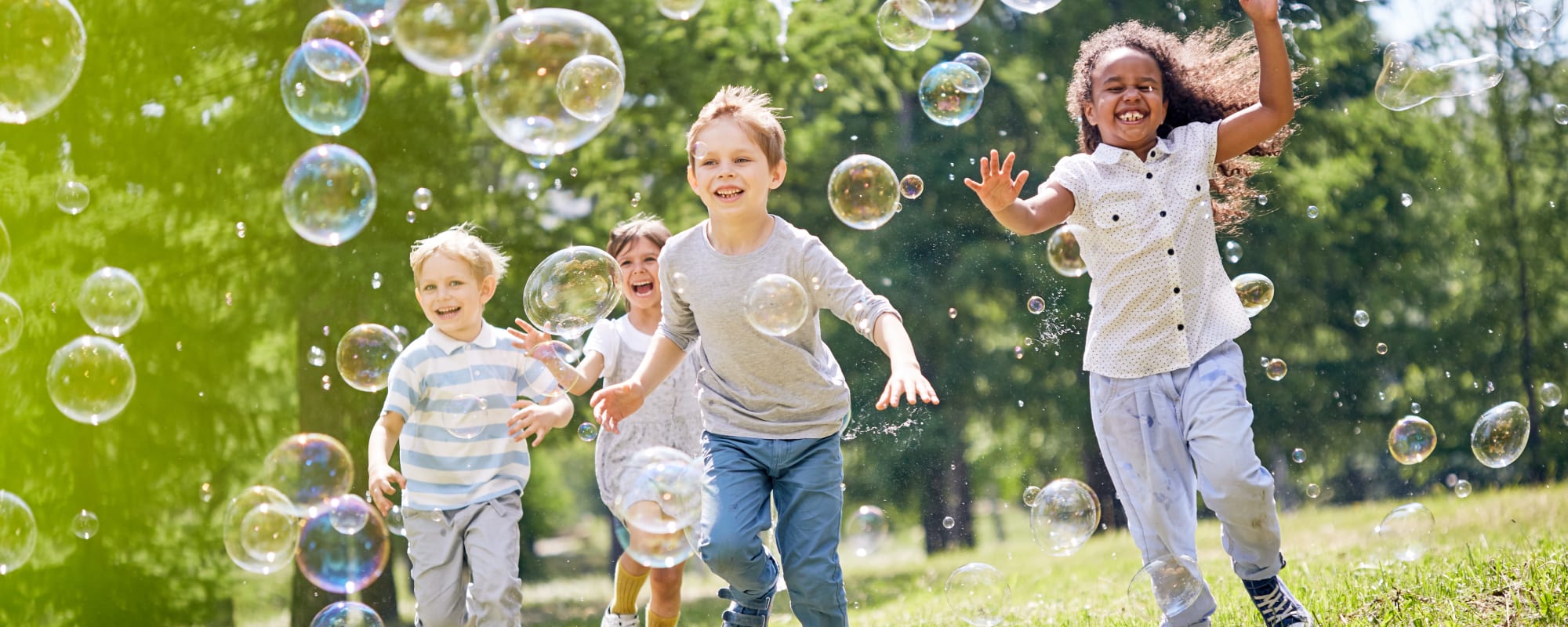 Children running and playing with bubbles in a field near Parkway in Joint Base Lewis McChord, Washington