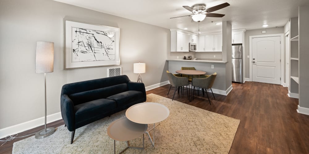 Living room and dining area of a model apartment with a ceiling fan and wood-style flooring at Summerhill Terrace Apartments in San Leandro, California