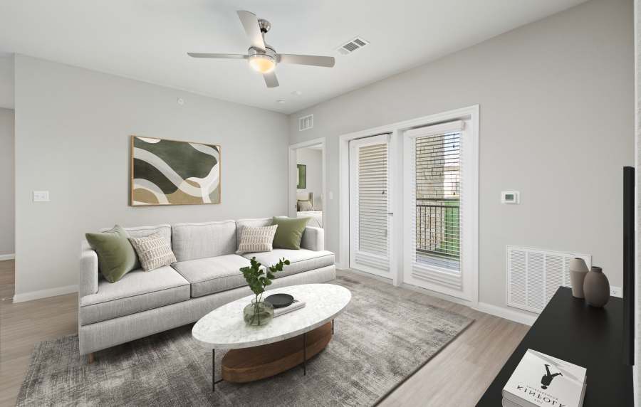 Bright living room with wood-style flooring, modern sofa, and large windows opening to a balcony at Preserve at Gresham Lake in Raleigh, North Carolina