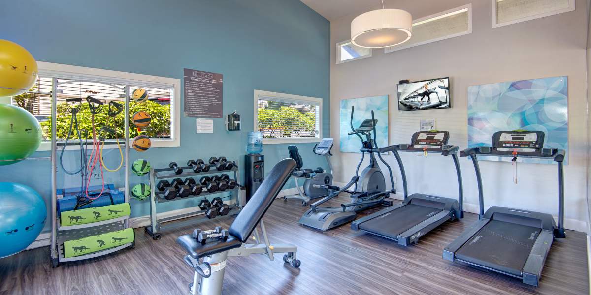 Fitness center with cardio machines and free weights at Latitude Apartments in Everett, Washington