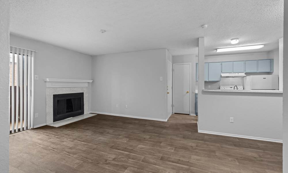 Spacious living room with fireplace and access to patio at Pine Oaks Apartments in Mesquite, Texas