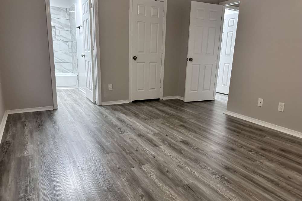 Unfurnished bedroom with wood-style flooring and access to bathroom at The Gardens At Pryor Creek in Pryor, Oklahoma