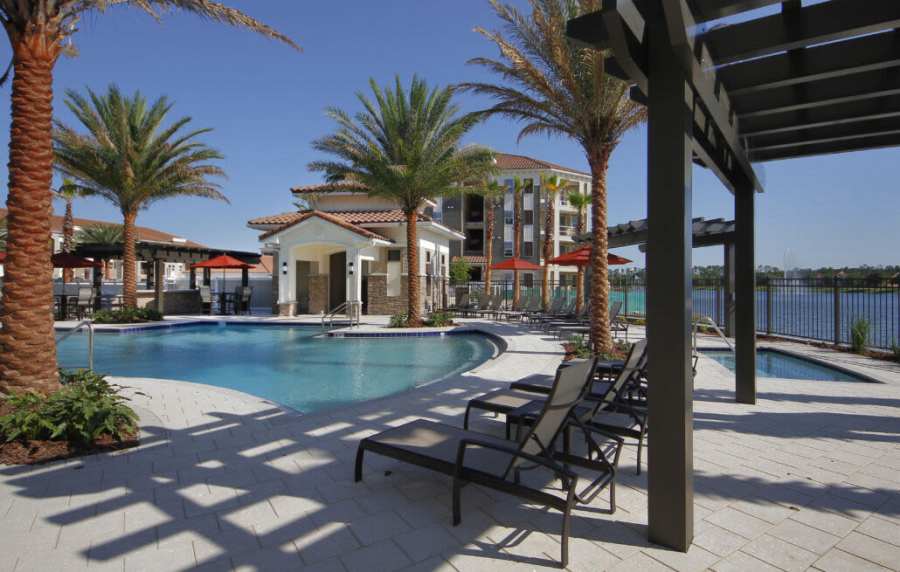 Sparkling pool with lounge chairs and palm trees by the water at Messina Luxury Apartments in New Smyrna Beach, Florida