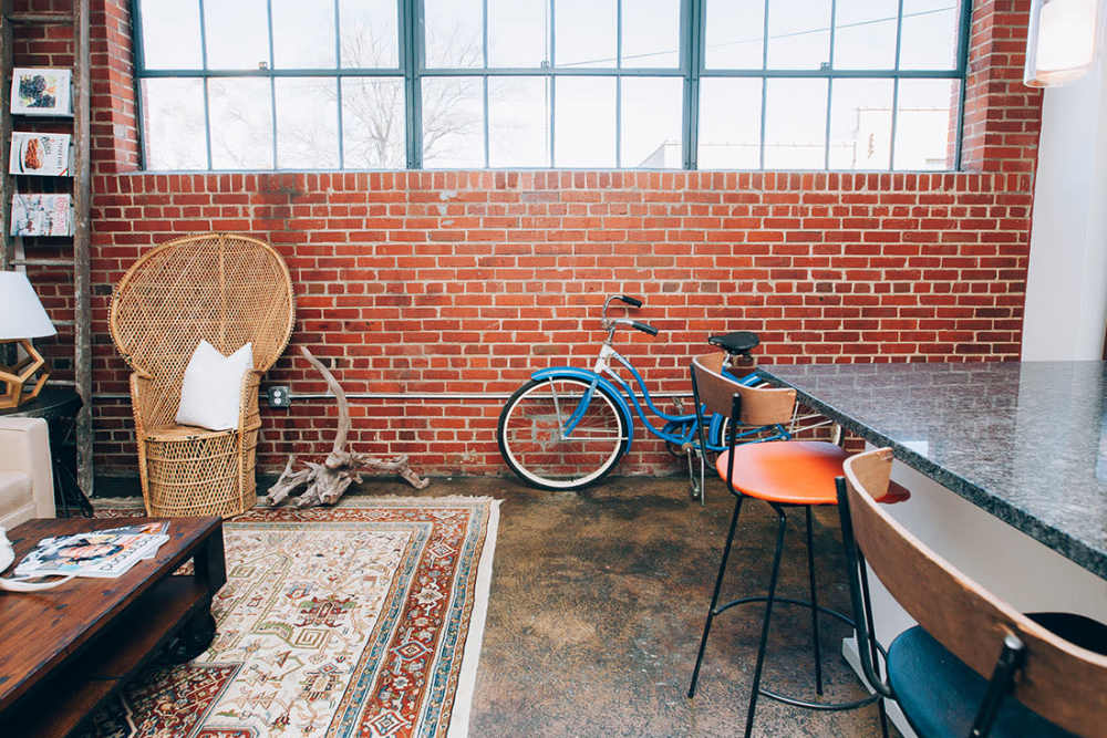 Stylish open layout with exposed brick walls at Courtyard Lofts at Scott’s Addition in Richmond, Virginia