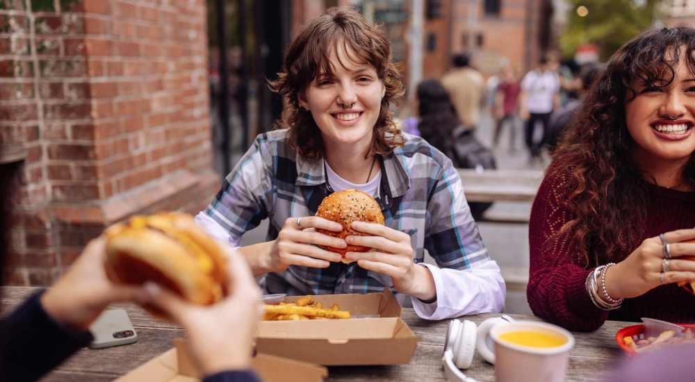 Three people eating burgers and fries at Atrium Gardens in Arlington, Texas 
