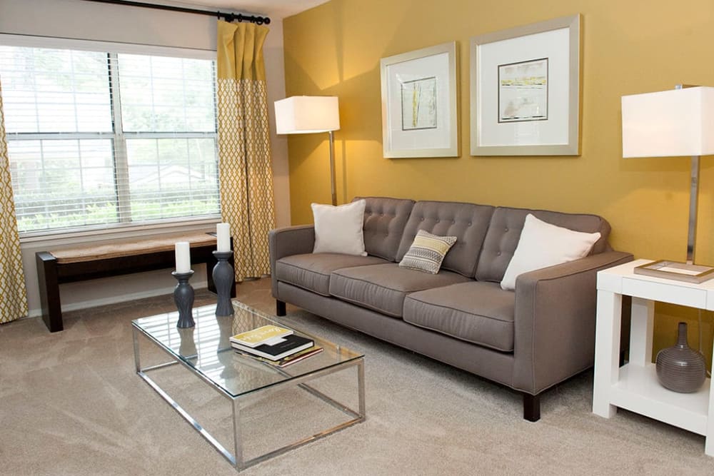 Model living room with cheerful yellow accent wall at Castlegate Collier Hills in Atlanta, Georgia