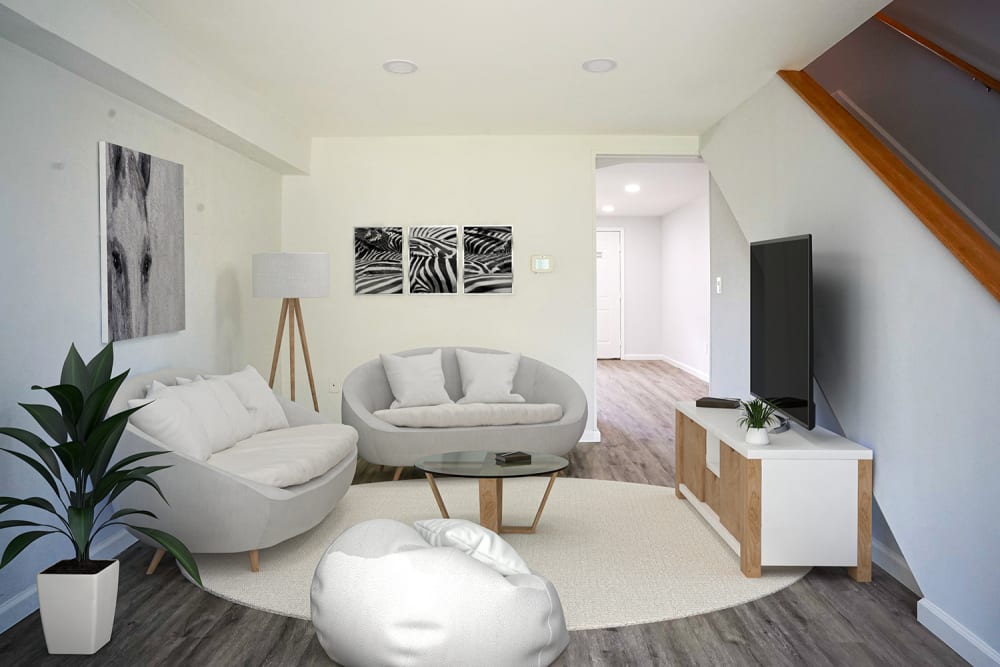 Bright living room with wood-style flooring, modern furniture, and decorative plants at Dutch Village Apartments in Baltimore, Maryland