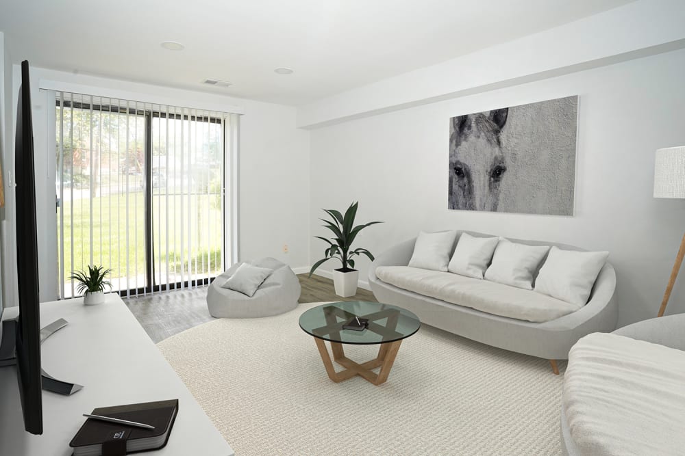 Bright living room with modern furniture, large windows, and textured wall art at Dutch Village Apartments in Baltimore, Maryland