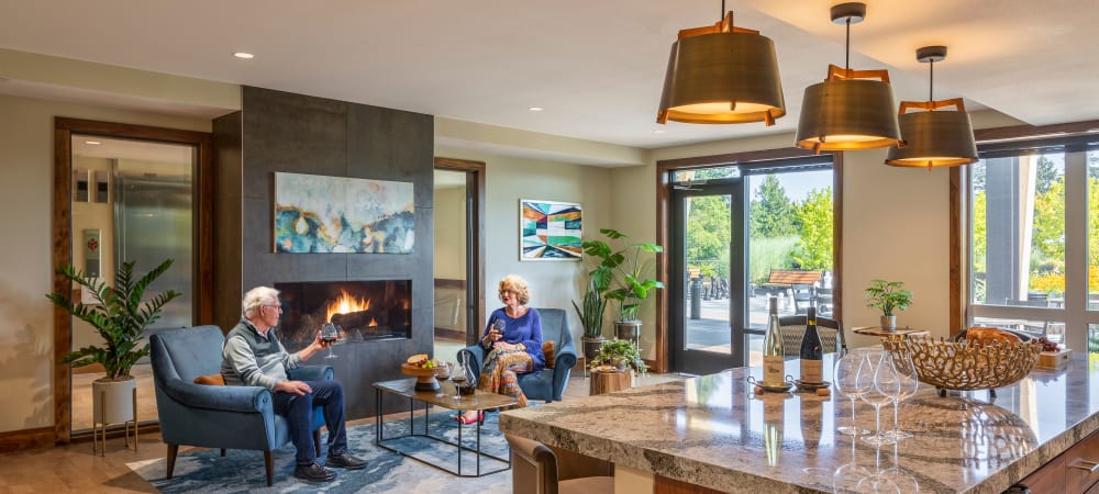 Two residents sitting by a fireplace at The Springs at Lake Oswego in Lake Oswego, Oregon