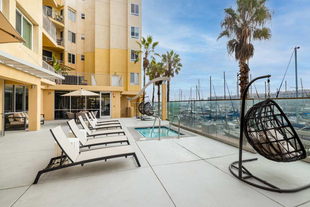 Luxury white lounge chairs by a pool at Capri Apartments in Marina Del Rey, California