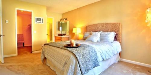 Cozy bedroom with large bed and dressing table unit at Countryside Apartments in Poway, California
