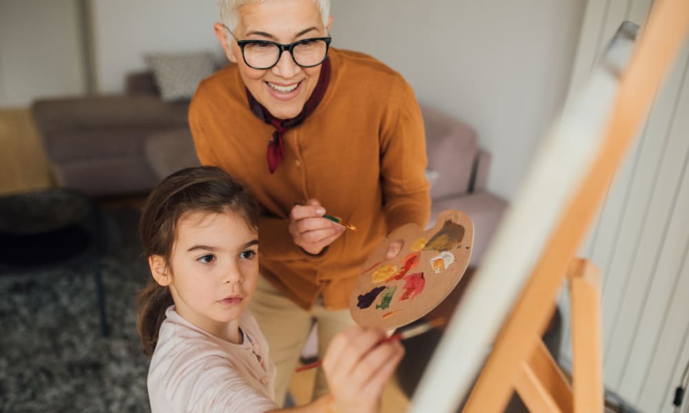 A resident teaching a child how to paint at Ativo Senior Living of Yuma in Yuma, Arizona.