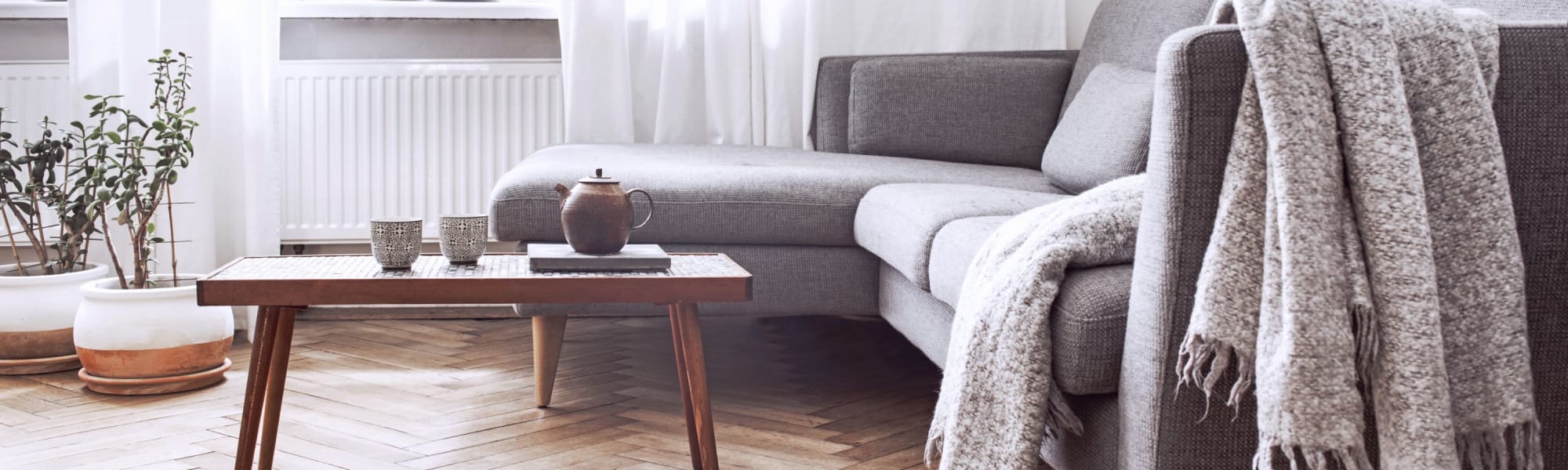 A close-up view coffee table with teapot and large living room sofas behind  at West Hartford Collection in West Hartford, Connecticut