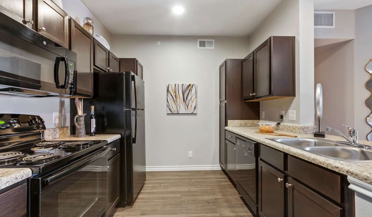Kitchen with wood cabinet and black appliances at Canyon House in New Braunfels, Texas