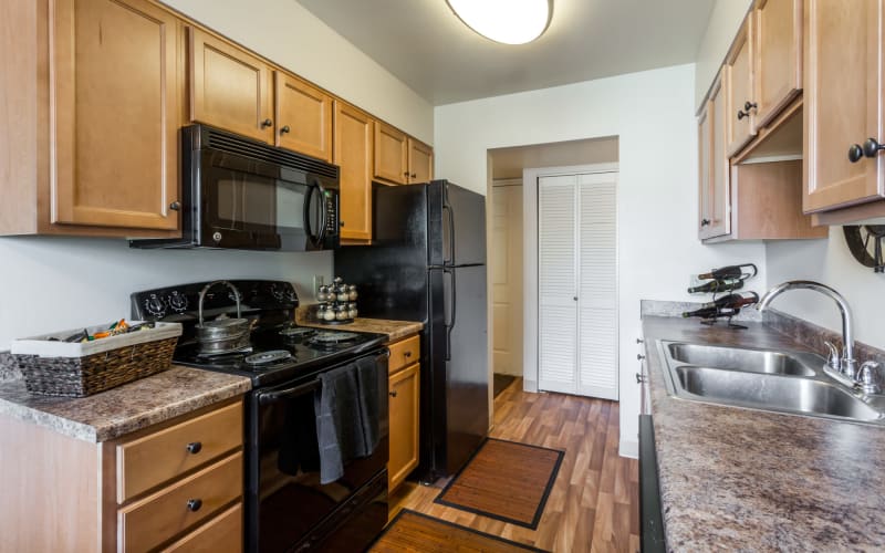 Oak cabinetry and black appliances in a kitchen at Royal Ridge Apartments in Midvale, Utah