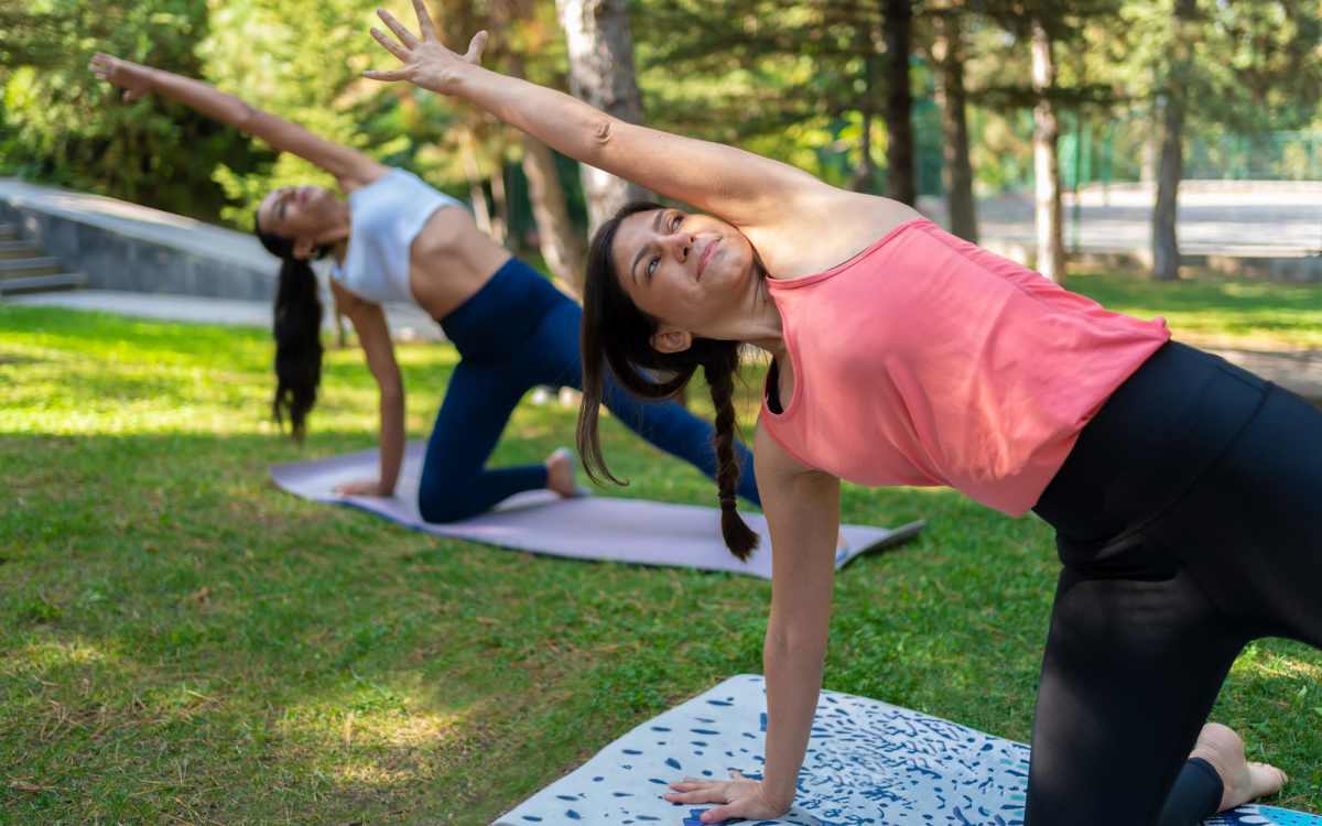 Friends doing yoga in park near Connection Angle Lake in SeaTac, Washington