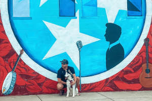 Resident and his dog by a mural at Martin Flats in Nashville, Tennessee