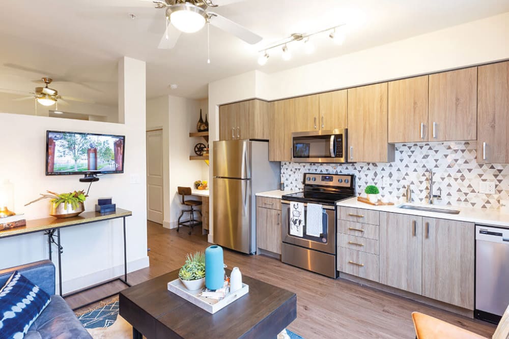 Custom cabinetry and a ceiling fan in a model home's open-concept kitchen and living areas at ArLo Apartments in Portland, Oregon