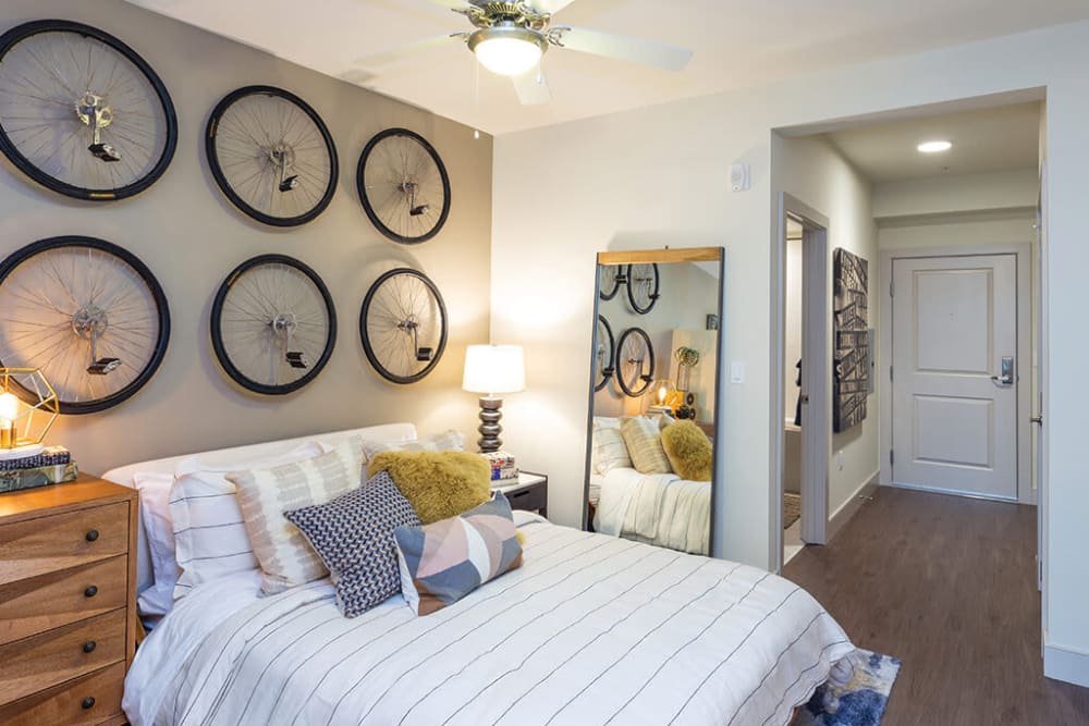 Well-furnished primary bedroom with a ceiling fan in a model home at ArLo Apartments in Portland, Oregon