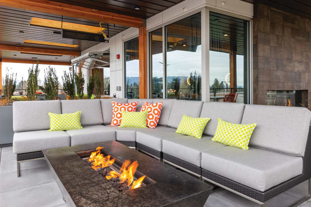 Fire pit surrounded by comfortable seating at the rooftop lounge at ArLo Apartments in Portland, Oregon