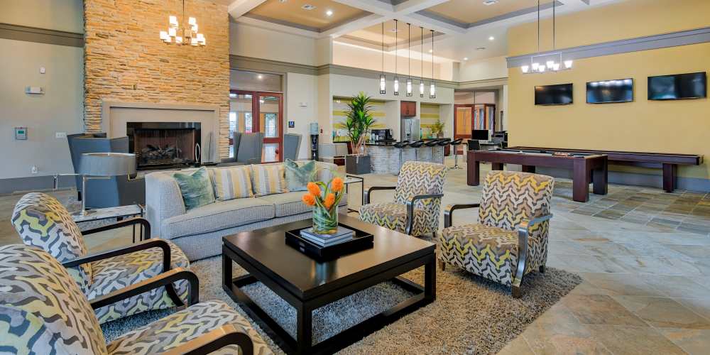 Spacious clubhouse with sofa, chairs, coffee table and fireplace at Grand Fountain in Richmond, Texas