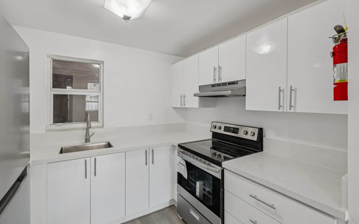 Kitchen showing a refrigerator and wall cabinets at El Jardin Apartments in Hollywood, Florida