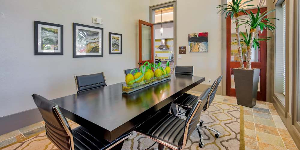 Community meeting room with large desk and chairs at Grand Fountain in Richmond, Texas