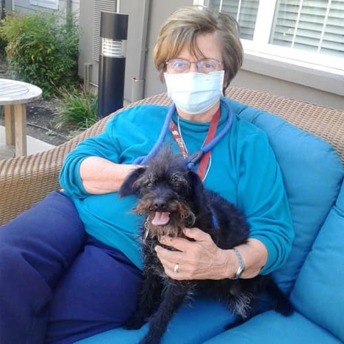 Resident seated outside beside her small black dog at The Oxford Grand Assisted Living & Memory Care in McKinney, Texas