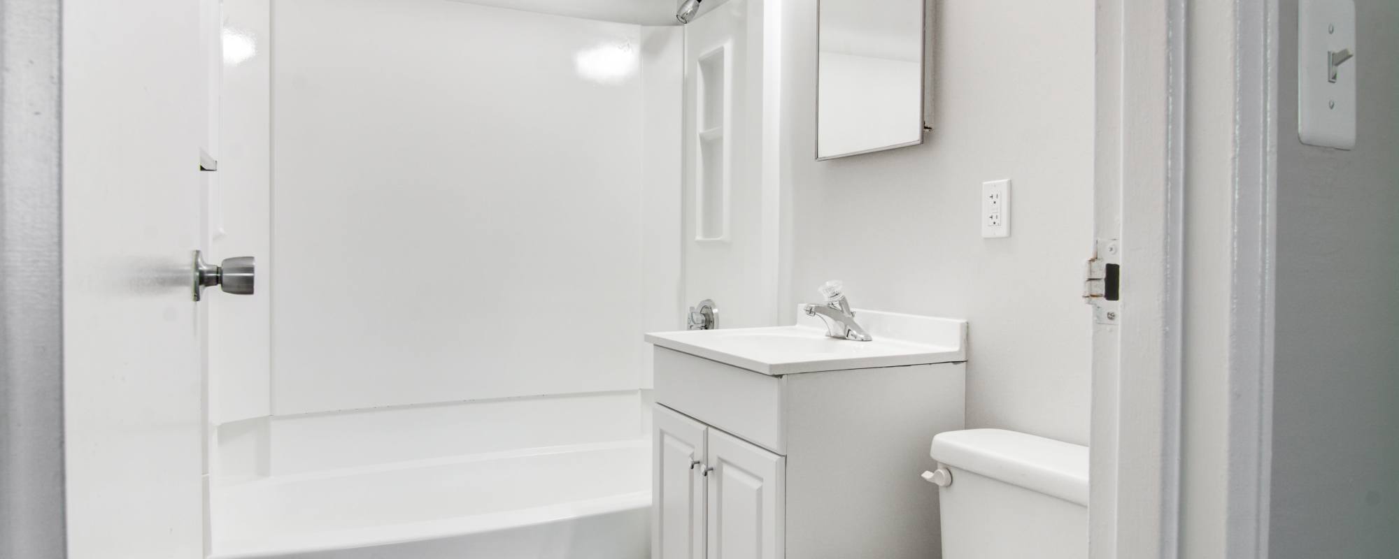 Bright bathroom with an all-white furnishings at Stony Brook Village in Hyde Park, Massachusetts
