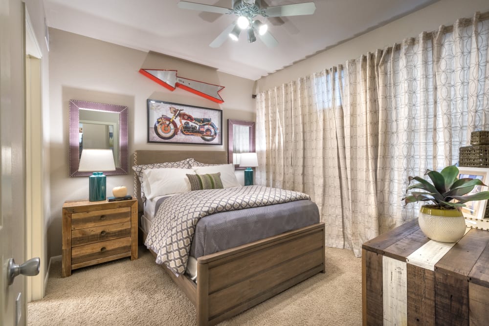 Model bedroom with a ceiling fan and plush carpeting at 75 West in Dallas, Texas