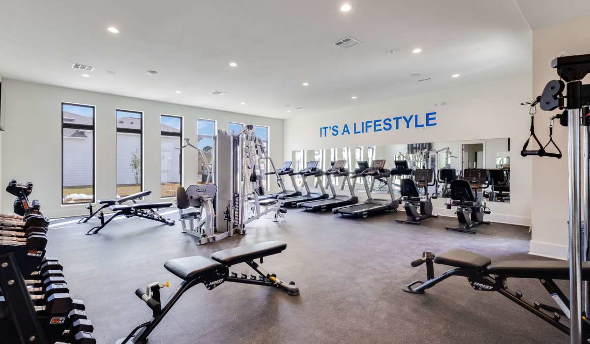 Fitness center with cardio machines, weight equipment, large windows, and motivational wall decor at Lakewood Villas in Bossier City, Louisiana