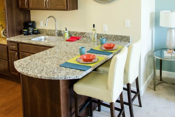 Kitchenette with granite counter tops and island seating at First & Main of Auburn Hills in Auburn Hills, Michigan
