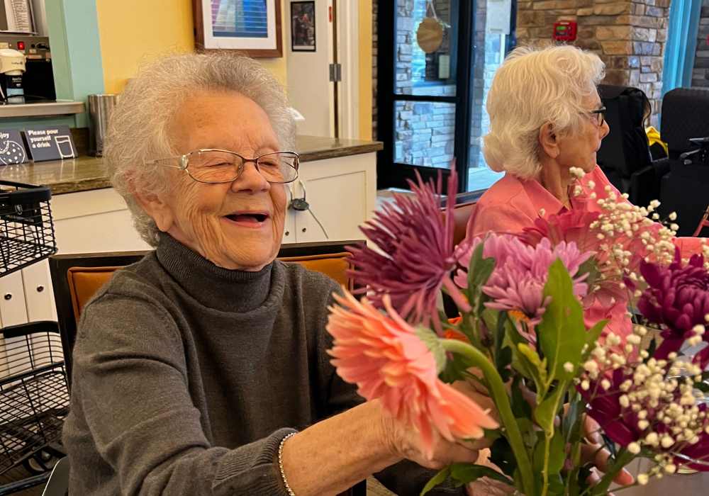 Residents holding flowers and laughing at Merrill Gardens at Tacoma in Tacoma, Washington
