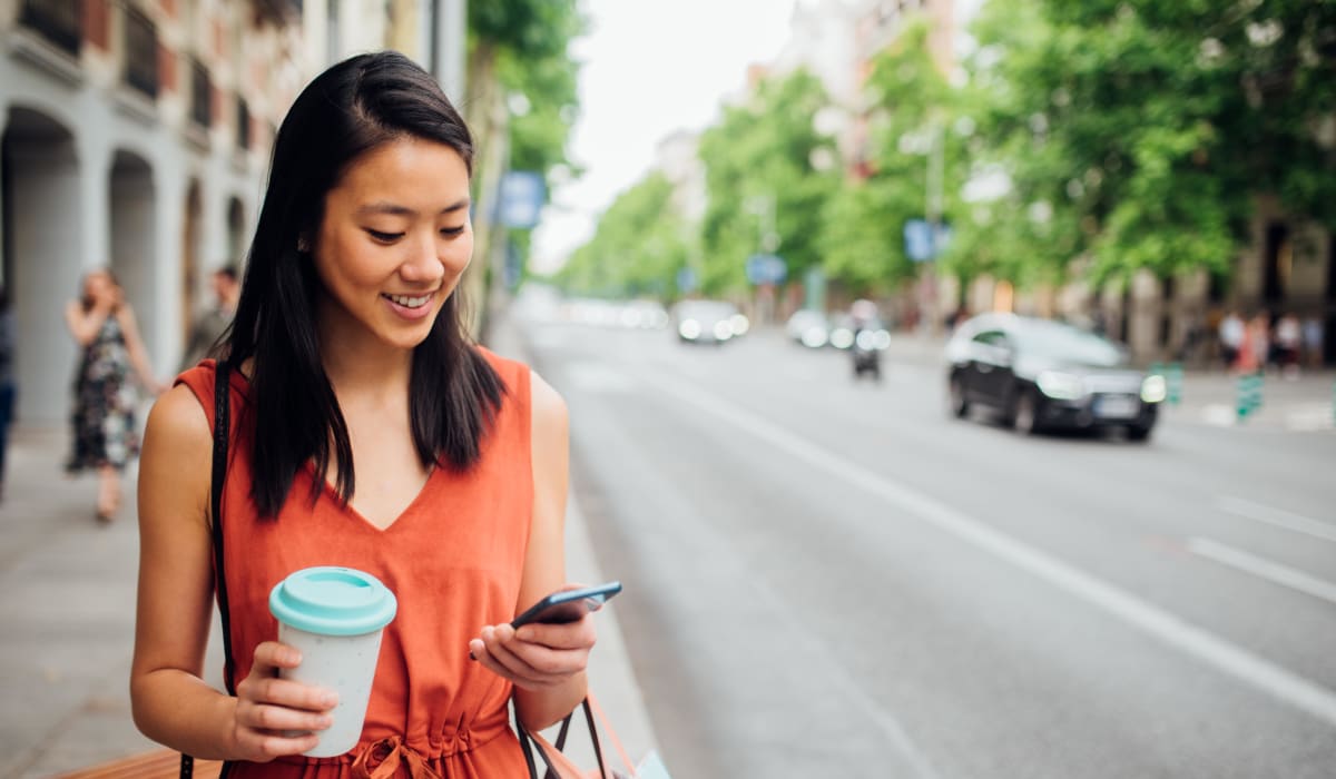 Resident checking her phone while walking to work with her morning coffee downtown near Rancho Los Feliz in Los Angeles, California