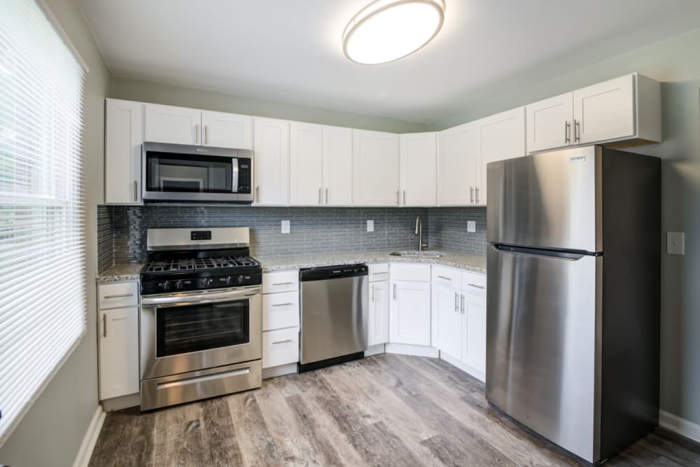 Kitchen with stainless steel appliances, granite countertops, and modern white cabinets