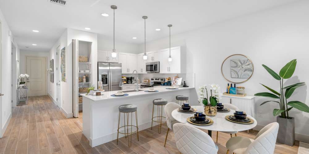 Modern kitchen with stainless steel appliances, granite countertops, and stylish dining area with elegant table setting at Solera at Avalon Trails in Delray Beach, Florida