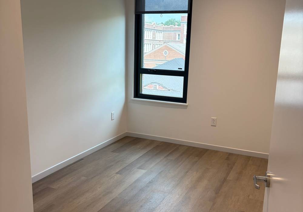 Modern bedroom with wood-style flooring at Penn Lincoln Apartments in Wilkinsburg, Pennsylvania