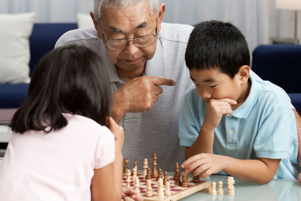 Resident playing chess with grandkids at Merrill Gardens at Hillsboro in Hillsboro, Oregon. 