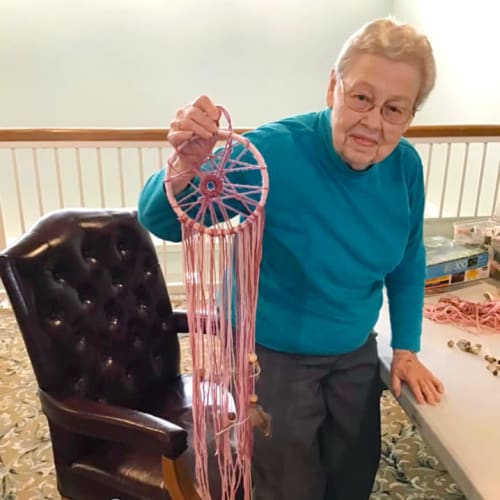 A happy resident holding up a pink dreamcatcher at Canoe Brook Assisted Living & Memory Care in Catoosa, Oklahoma