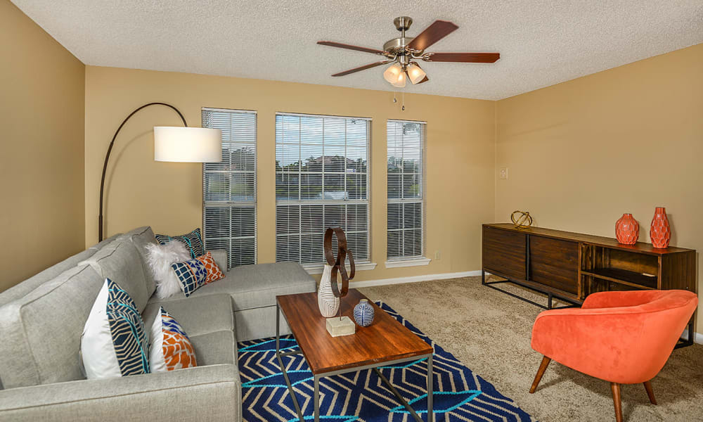 Living room with wall-to-wall carpeting and a ceiling fan in a model home at Royal St. George at the Villages Apartment Homes in West Palm Beach, Florida
