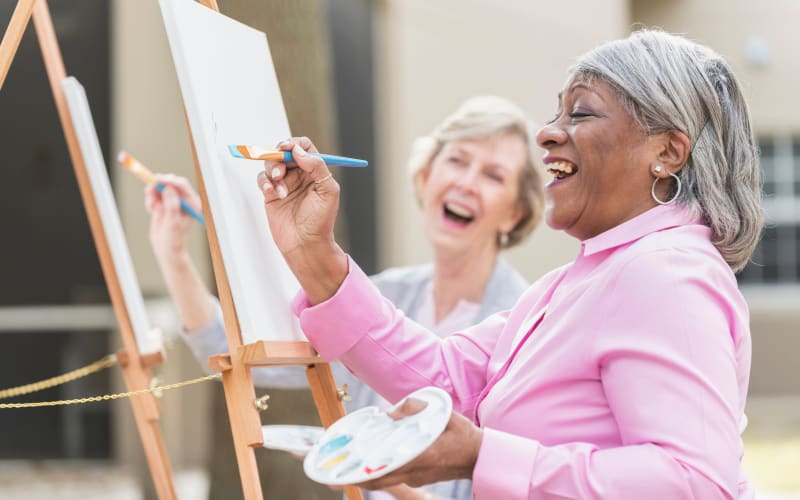 Resident laughing together while painting at Citrus Place in Riverside, California